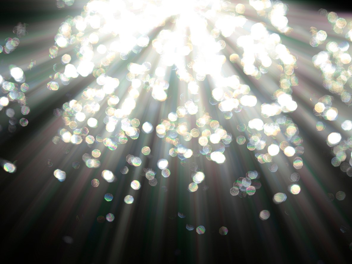 Sunlight sparkling through the dark, with glowing bokeh effects.