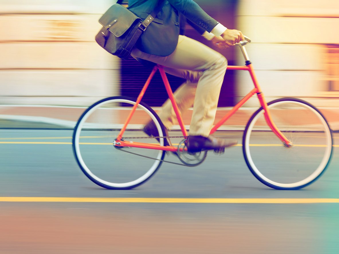 A person riding a red bicycle with a blurred background, suggesting motion and speed.